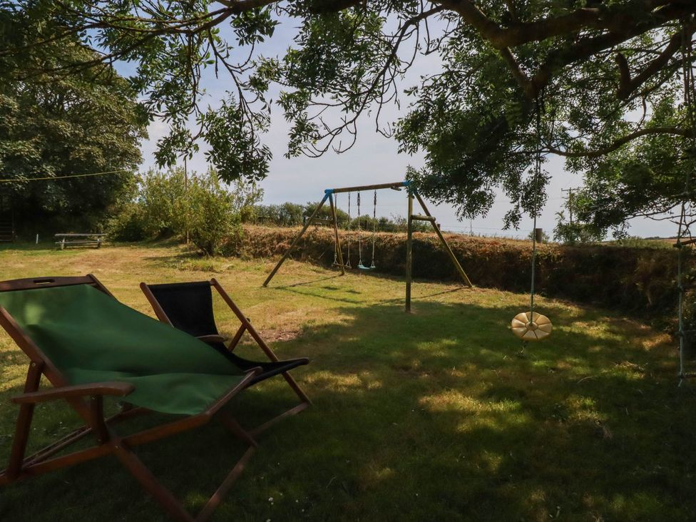 A garden with a swing set and deck chair at The Granary 