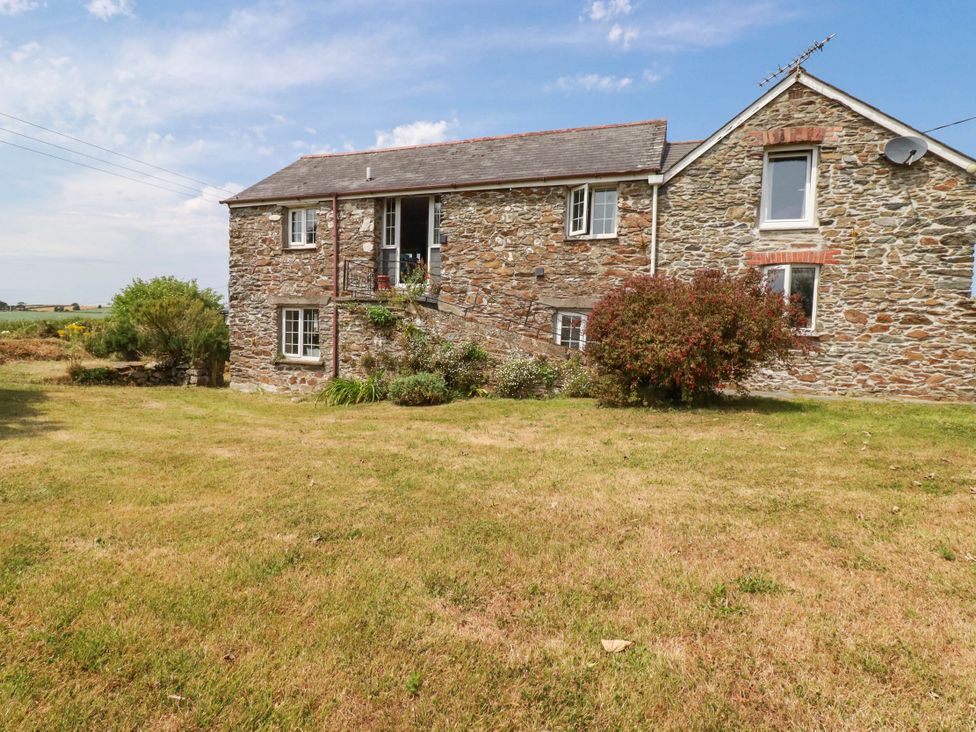 A stone house with stairs and bush in front at The Granary