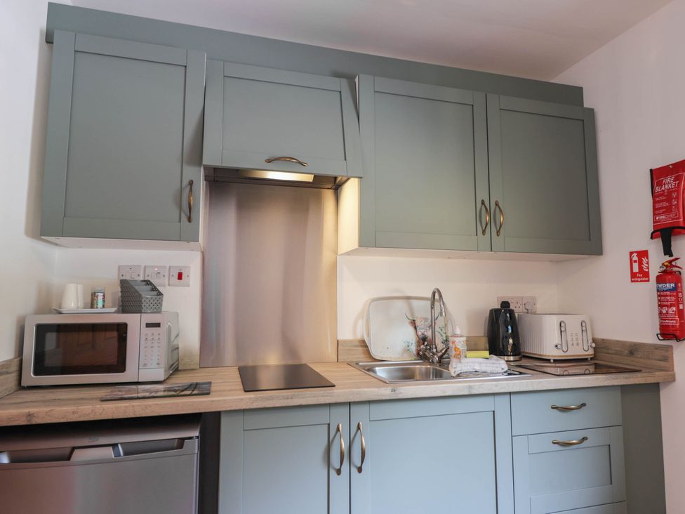 A kitchen with cabinets, appliances, and sink at Park House Cannich Holiday Retreat in Cannich