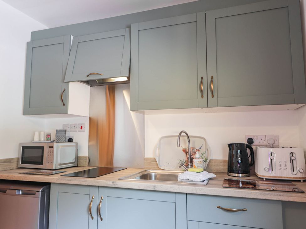 A kitchen with cabinets, sink, microwave, kettle, and toaster at Park House Cannich Holiday Retreat in Cannich