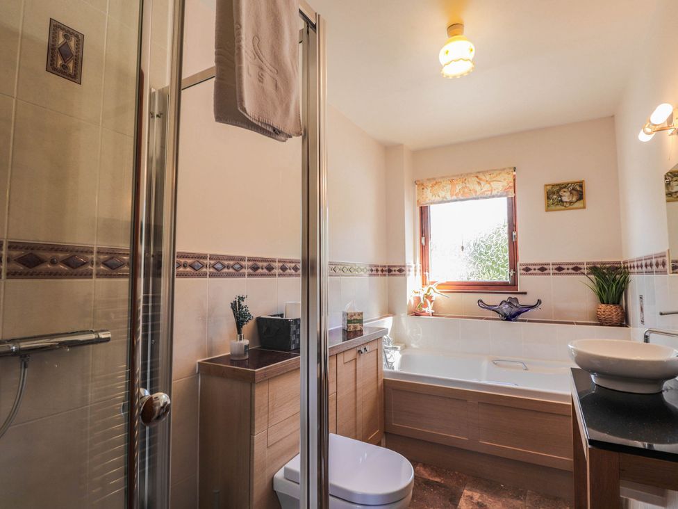 A bathroom with shower, bathtub, toilet, and sink at Park House Cannich Holiday Retreat in Cannich