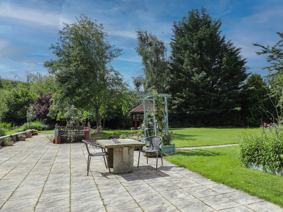A garden with a stone table and chairs at Park House Cannich Holiday Retreat Cannich