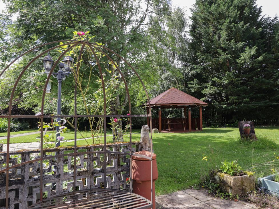 A garden with a gazebo and a bench at Park House Cannich Holiday Retreat, Cannich
