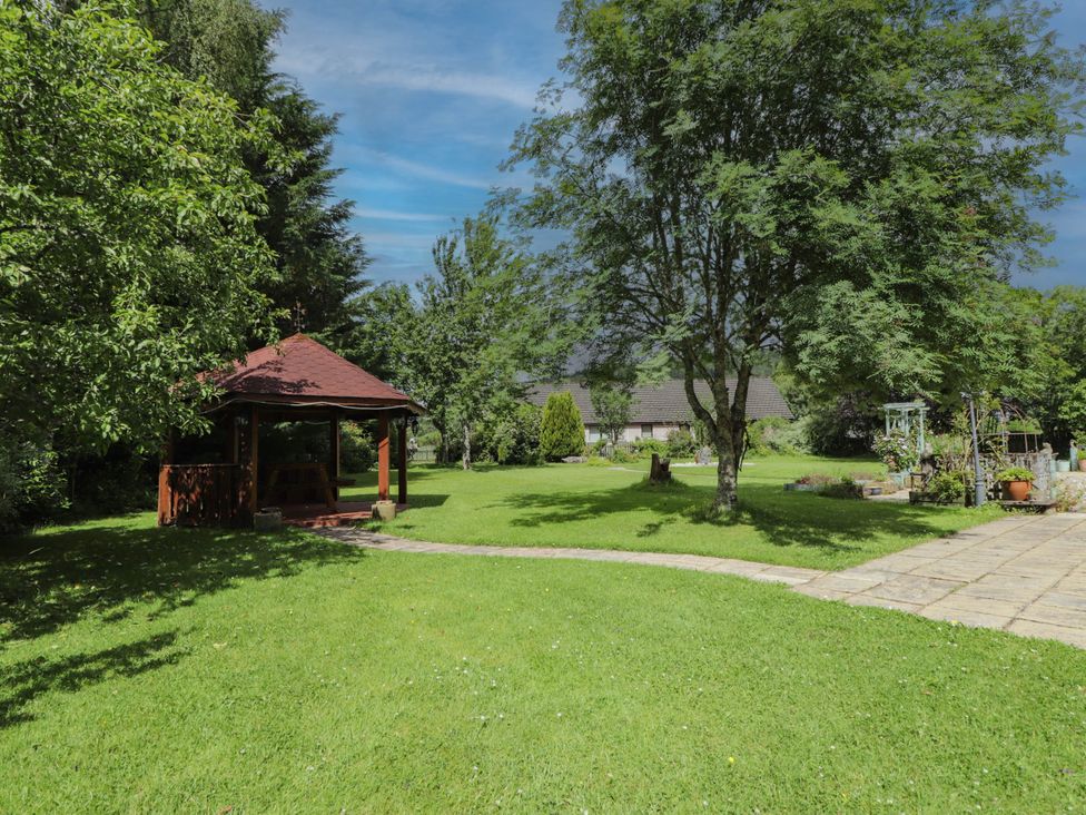 A garden with a gazebo and trees at Park House Cannich Holiday Retreat Cannich