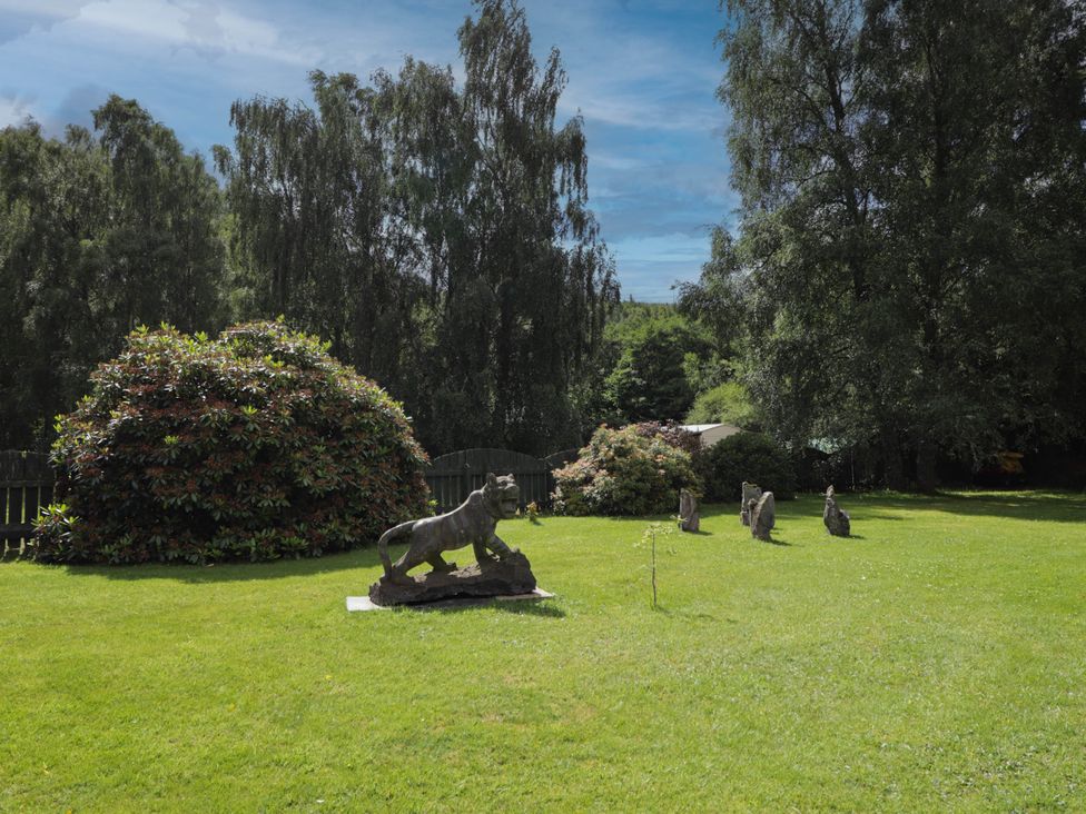 A garden with a sculpture and bushes at Park House Cannich Holiday Retreat in Cannich