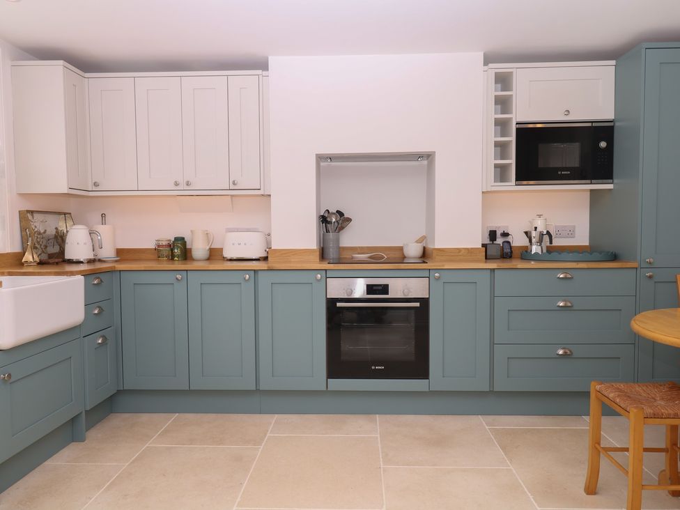 A kitchen with cabinets, countertop, oven, and dining table at Tower View Cottage in Lympstone