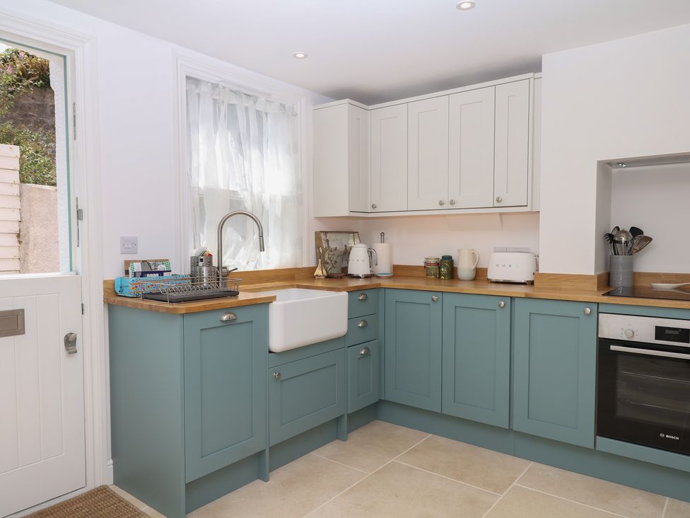 A kitchen with cabinets, sink, and appliances at Tower View Cottage in Lympstone
