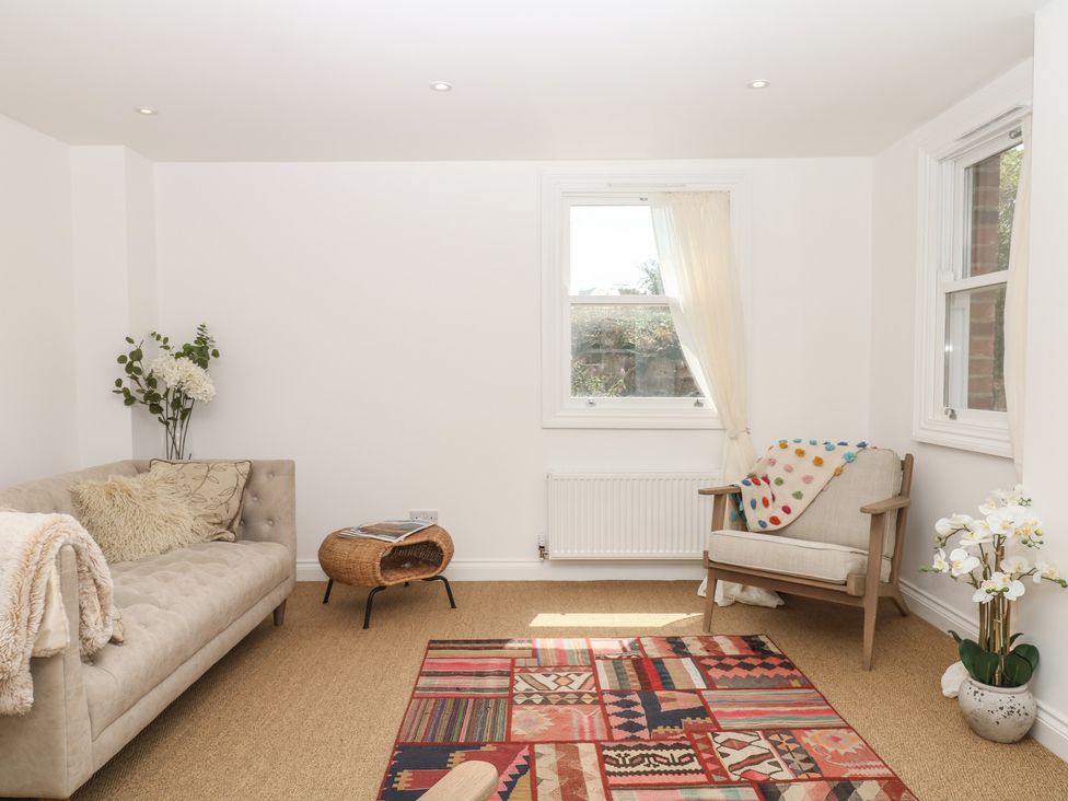 A living room with a sofa, chair, and rug at Tower View Cottage in Lympstone