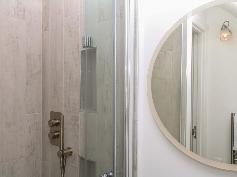 A shower with controls and a mirror at Tower View Cottage in Lympstone
