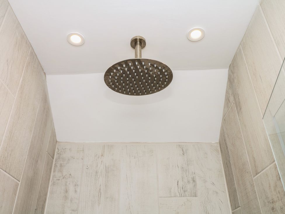 A shower with a large shower head at Tower View Cottage in Lympstone