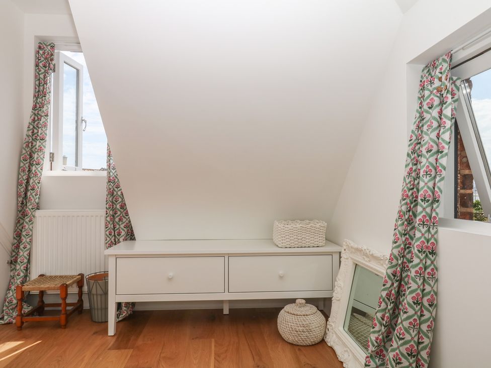 An attic room with a window and storage unit at Tower View Cottage in Lympstone