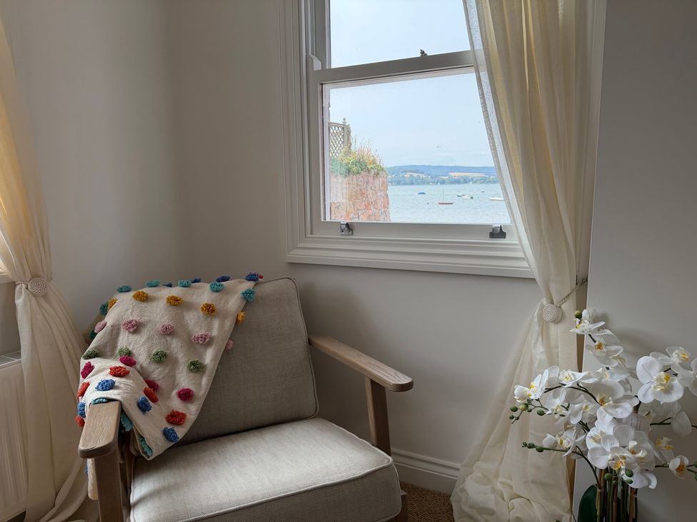 A living room with a chair by the window at Tower View Cottage in Lympstone