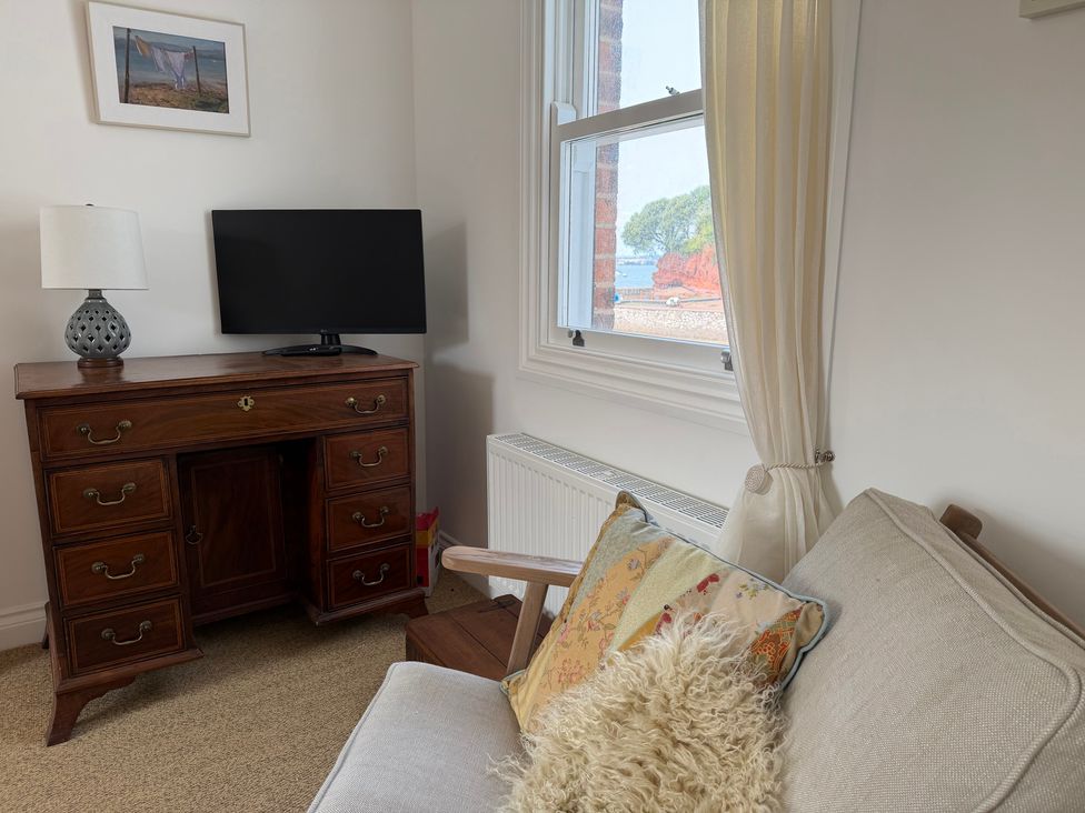 A living room with a television, lamp and dresser at Tower View Cottage in Lympstone