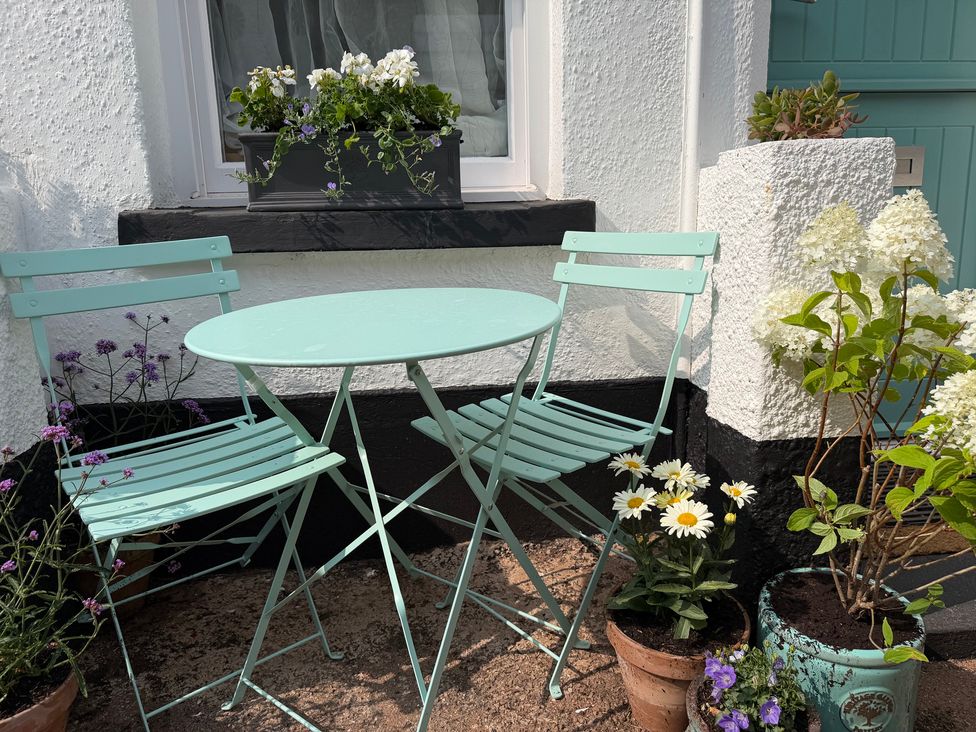 A table and chairs with flower pots in an outdoor area at Tower View Cottage Lympstone