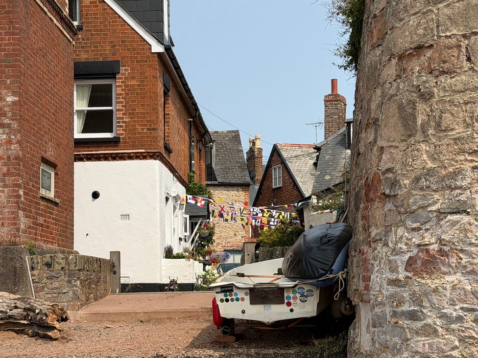 An outdoor view with houses, a boat, and flags at Tower View Cottage in Lympstone