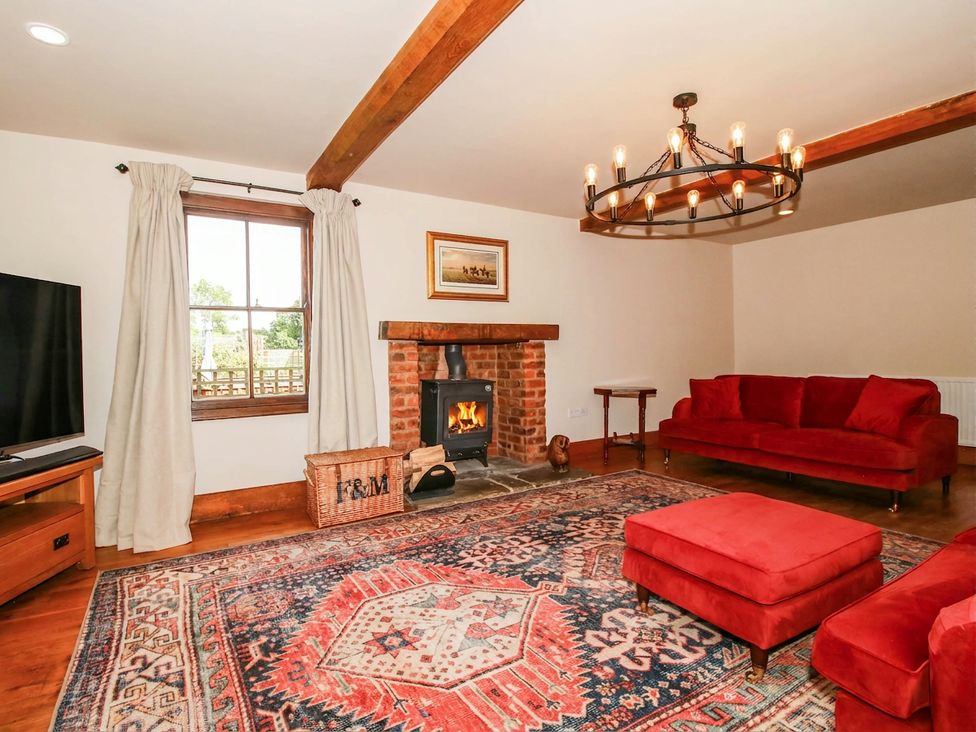 A living room with a fireplace and red sofas at Stone House Farm in Cobnash near Leominster