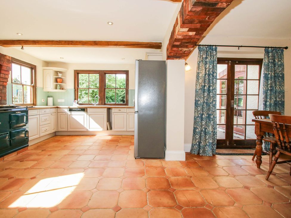 A kitchen with a refrigerator and dining table at Stone House Farm in Cobnash near Leominster