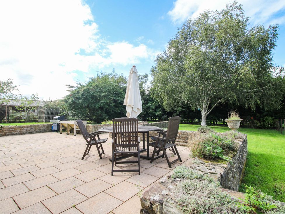 A garden with a table and chairs under an umbrella at Stone House Farm in Cobnash near Leominster