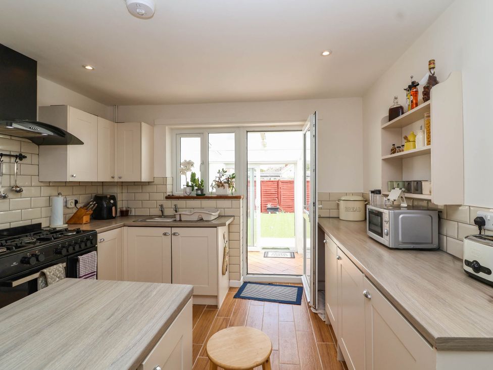 A kitchen with a stove, sink, and microwave at 56 Steart Gardens Burnham-on-Sea