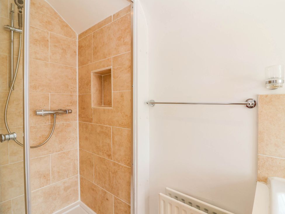 A bathroom with a shower and towel rail at 56 Steart Gardens Burnham-on-Sea