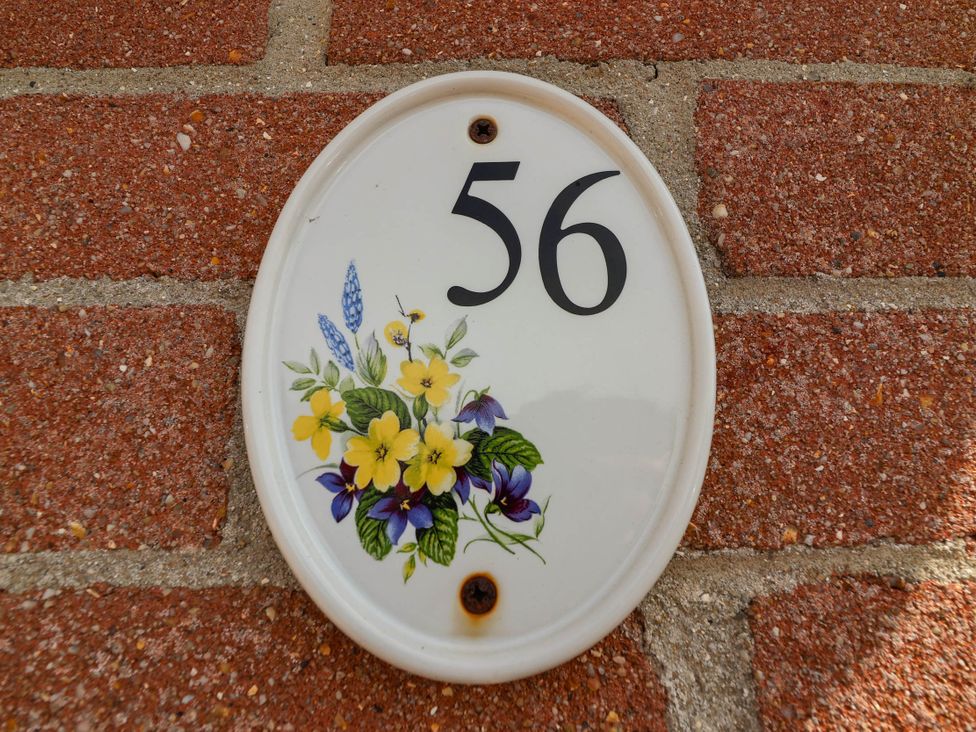 A house number 56 with floral design on a ceramic plate on a brick wall at 56 Steart Gardens Burnham-on-Sea
