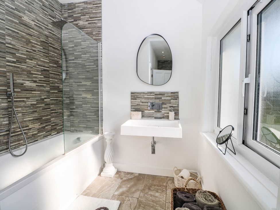 A bathroom with a shower, bathtub, sink and mirror at 41 Terminus Avenue Bexhill-On-Sea