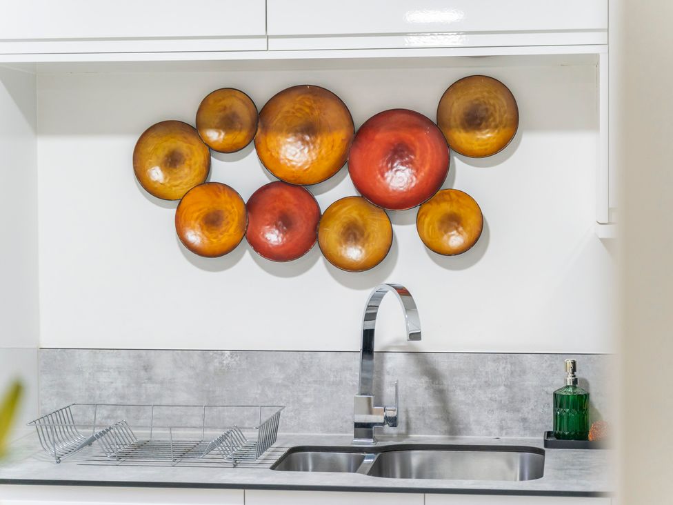 A kitchen with a sink and decorative bowls on the wall at 2 Pump House Birmingham
