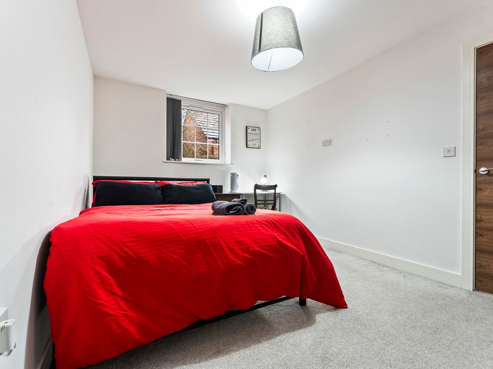 A bedroom with a red bed and a desk at 2 Pump House Birmingham