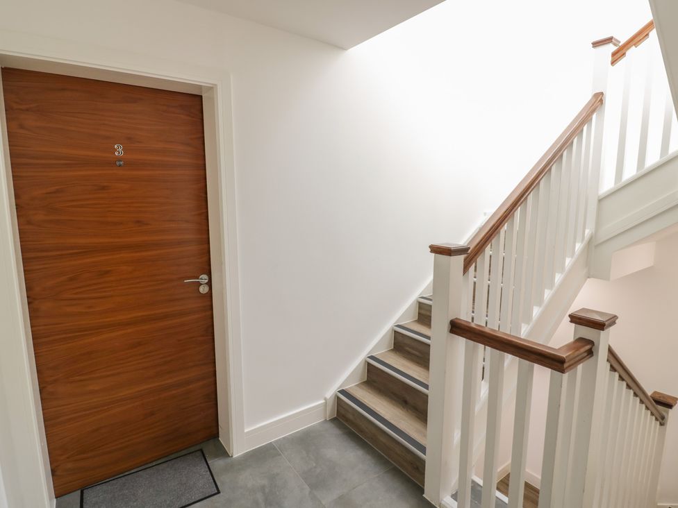 A stairway with a wooden door and white railings at 3 Pump House in Birmingham
