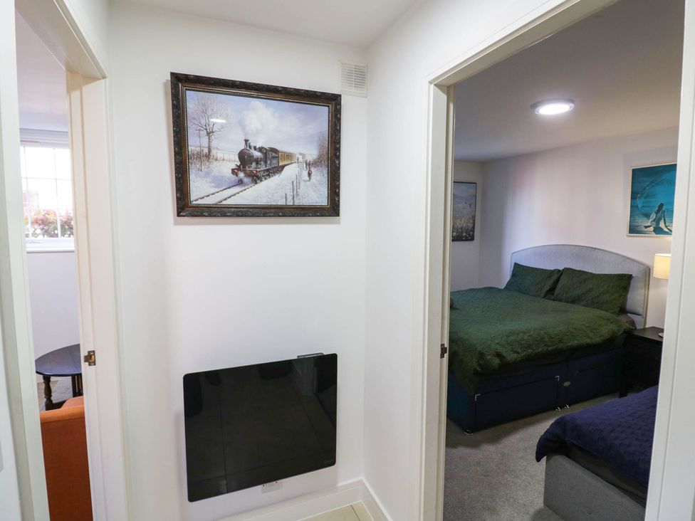 A hallway with a painting, TV, and doors to a bedroom at 4 Pump House in Birmingham