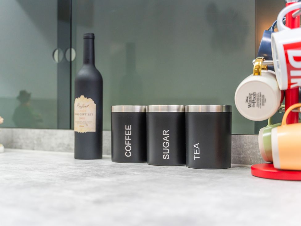 A kitchen countertop with canisters for coffee, sugar, tea and a wine bottle at 5 Pump House Birmingham