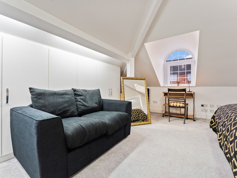 A bedroom with a sofa, desk, chair, and mirror at 5 Pump House in Birmingham