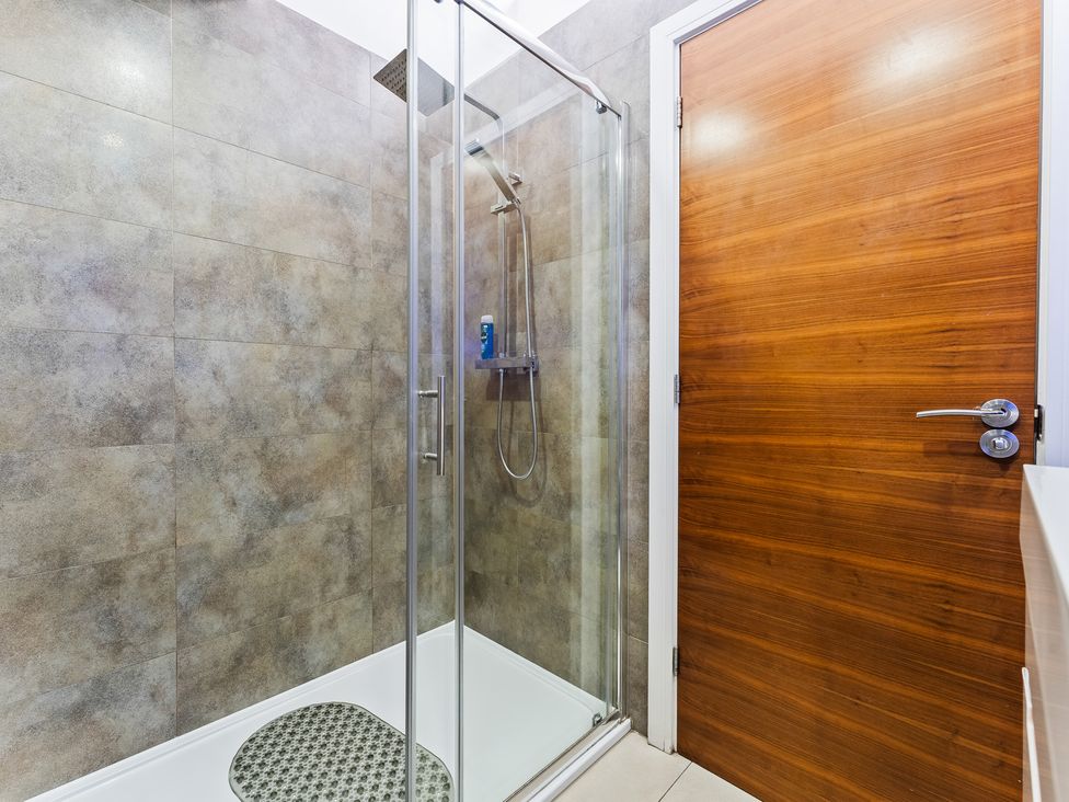 A bathroom with a shower enclosure and wooden door at 5 Pump House in Birmingham