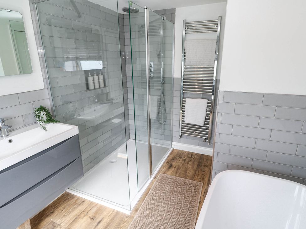 A bathroom with a shower, bathtub, sink and towel rail at The Lookout in Redruth