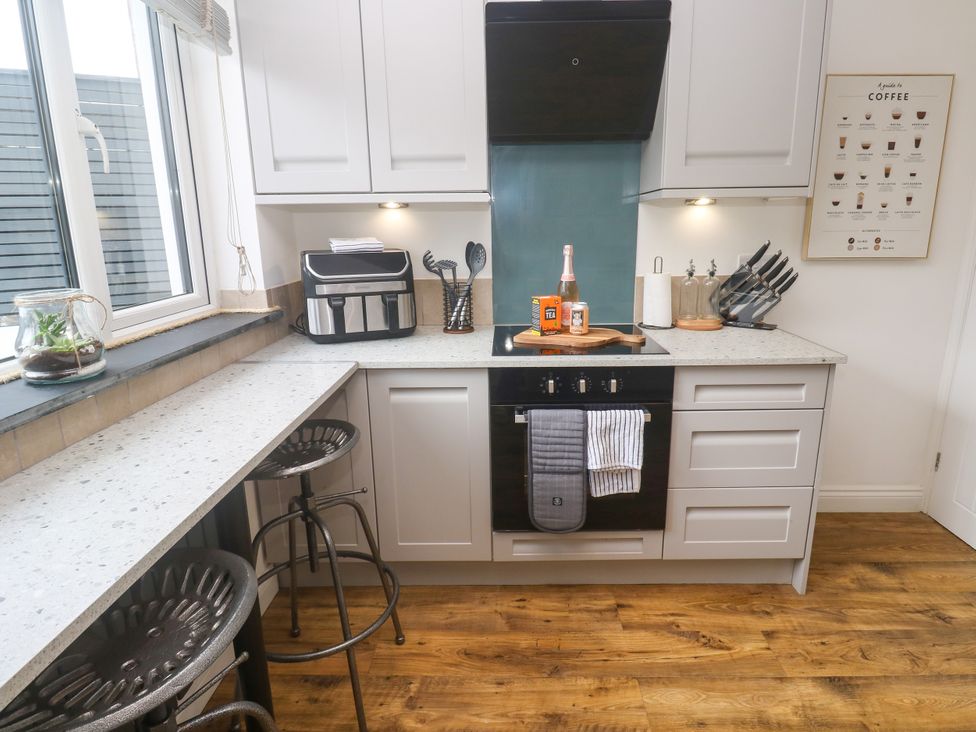 A kitchen with stove and bar stools at The Lookout in Redruth