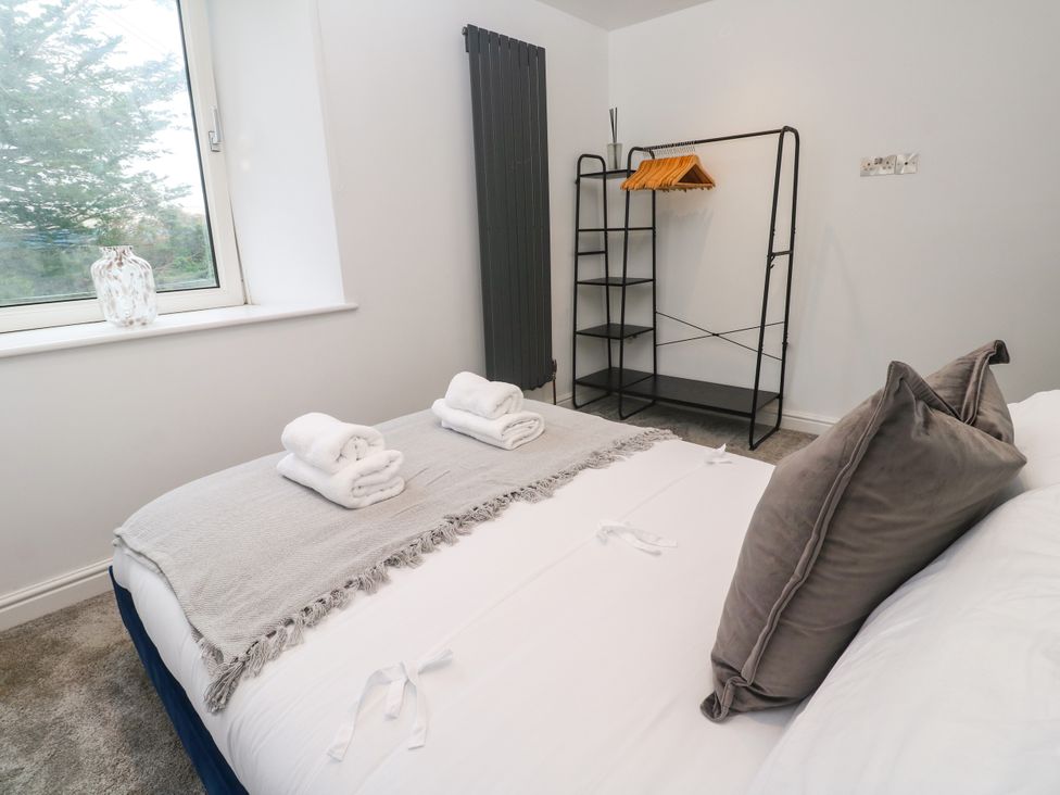 A bedroom with a bed, towels on top, and a hanging rack at The Lookout in Redruth