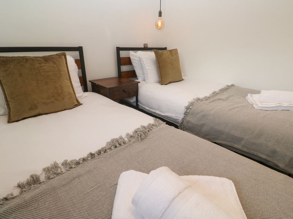 A bedroom with two beds and a bedside table at The Lookout in Redruth