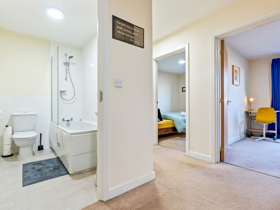 A bathroom with a bathtub and a hallway leading to a bedroom at Flat 34 Herbert James Close, Birmingham