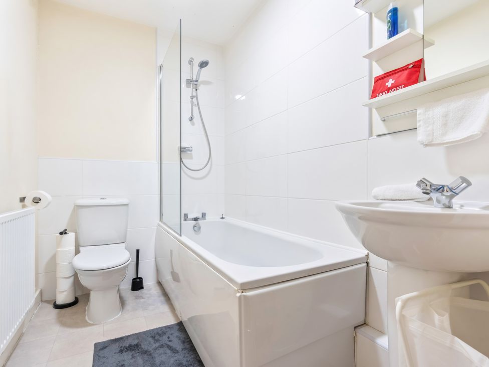 A bathroom with a toilet, shower over bathtub, sink, and radiator at Flat 34 Herbert James Close in Birmingham