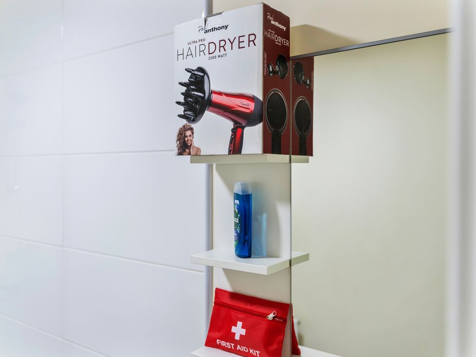 A hair dryer box and personal items on a shelf in a bathroom at Flat 34 Herbert James Close in Birmingham