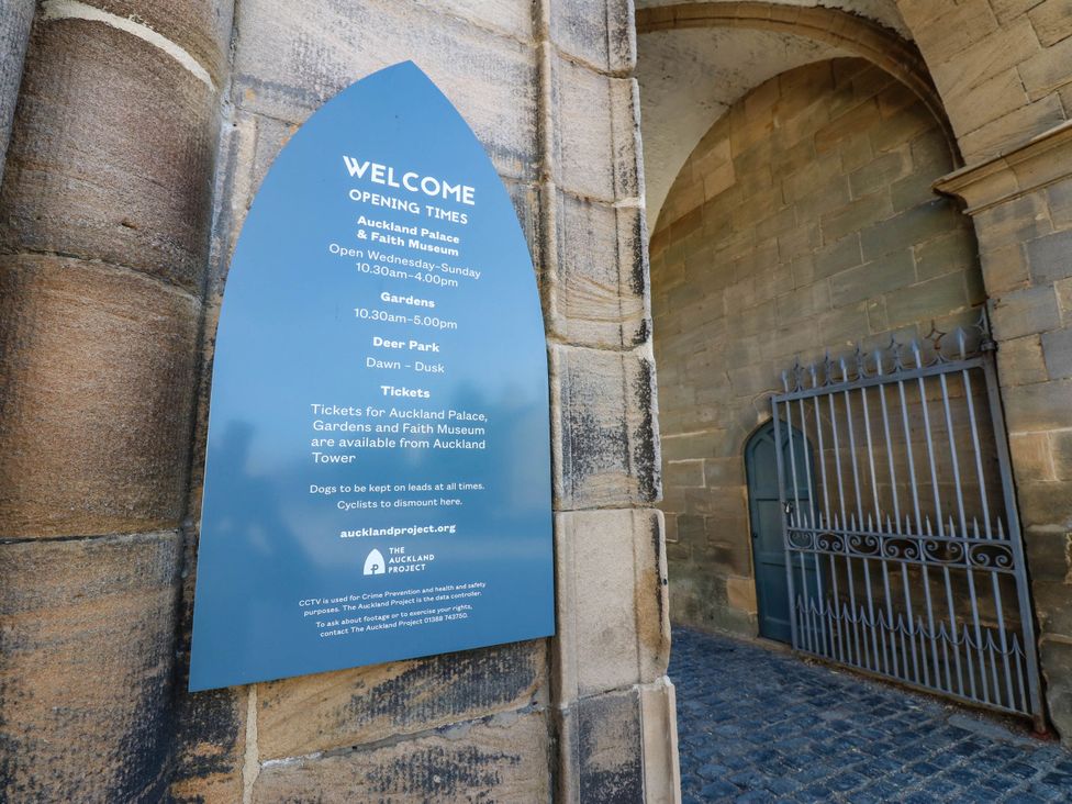 A welcome sign displaying opening times at Auckland Palace in Bishop Auckland