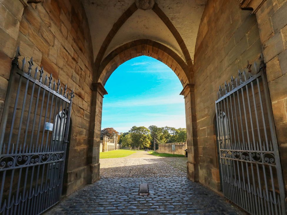 An archway with an open gate leading to a pathway and trees at Bishops Quarter - Barrington in Bishop Auckland