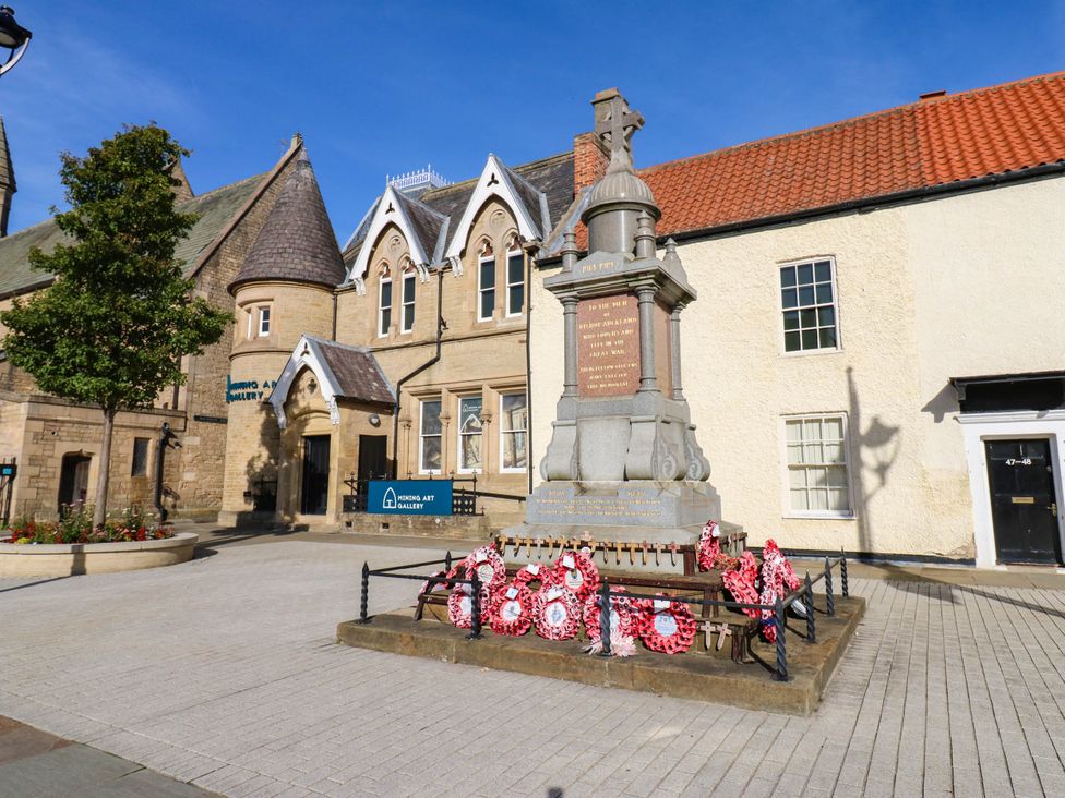 A monument with wreaths and buildings at Bishops Quarter - Barrington in Bishop Auckland