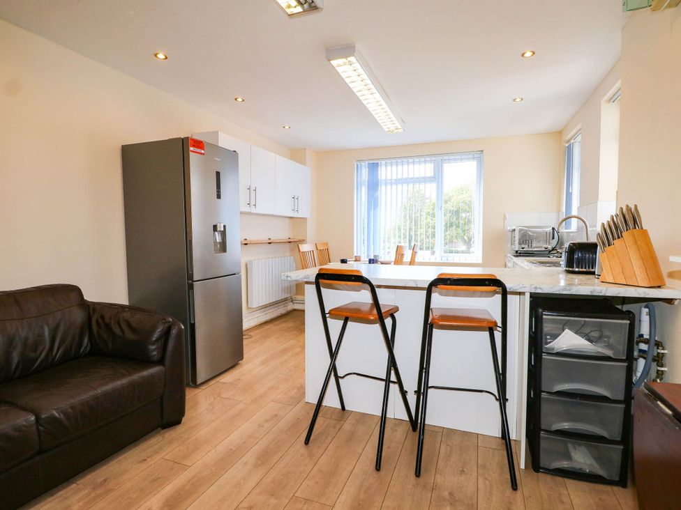 A kitchen with bar stools and appliances at 90 A Station Road New Milton