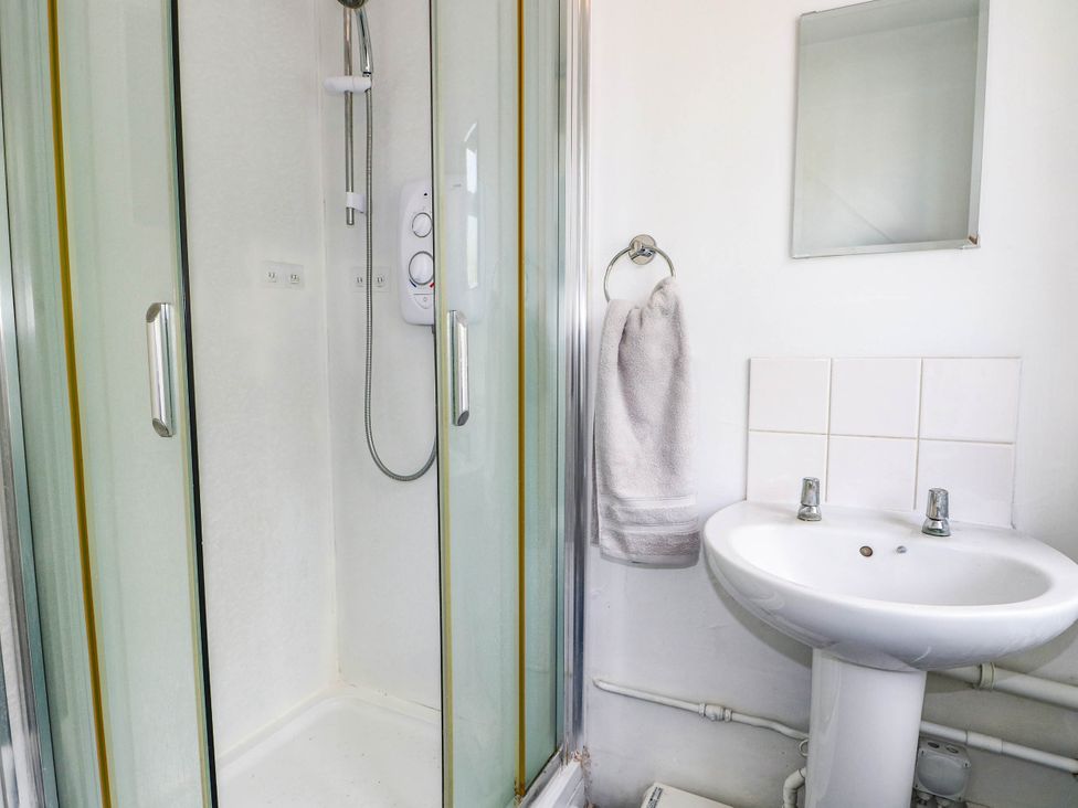 A bathroom with a shower, washbasin, and mirror at 90 A Station Road in New Milton