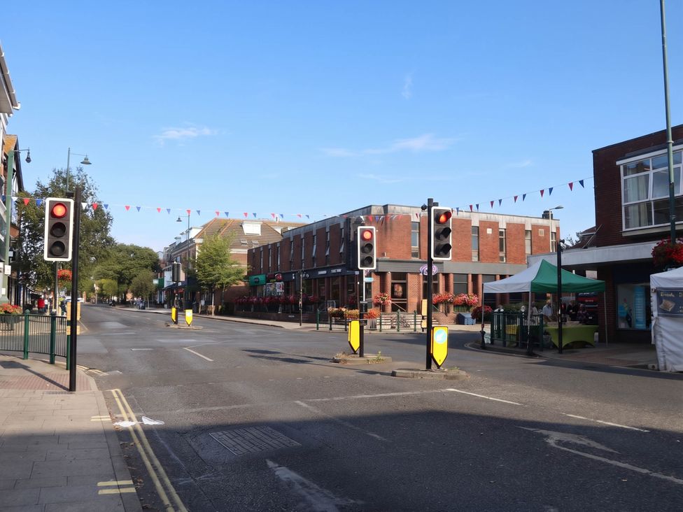 A street with traffic lights and buildings at 90 A Station Road in New Milton
