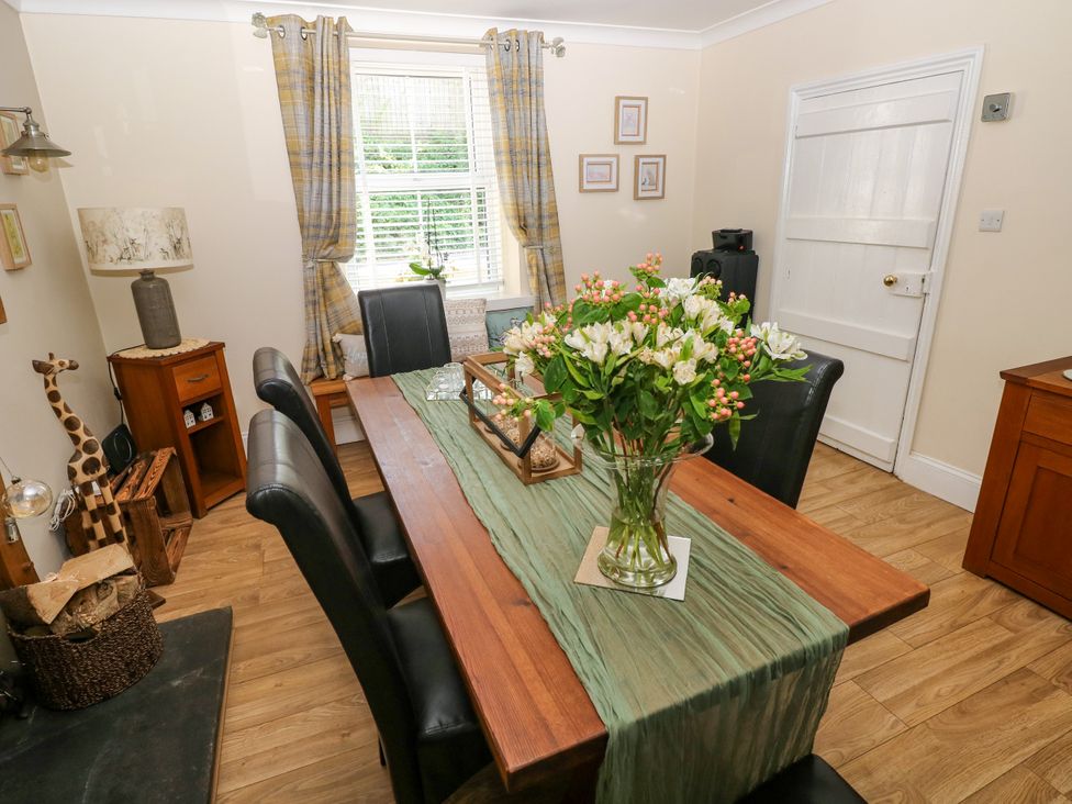 A dining room with a wooden table and chairs at St.Twynells Farm in Pembroke