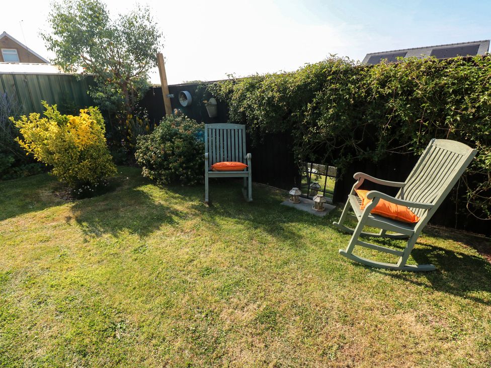 A garden with rocking chairs and bushes at St.Twynells Farm in Pembroke
