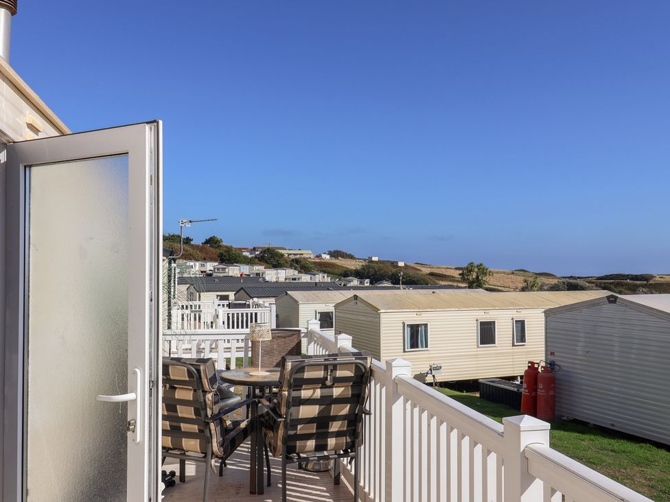 An outdoor area with chairs and a table overlooking caravans at Beech Walk 3 in Sandy Bay, Exmouth