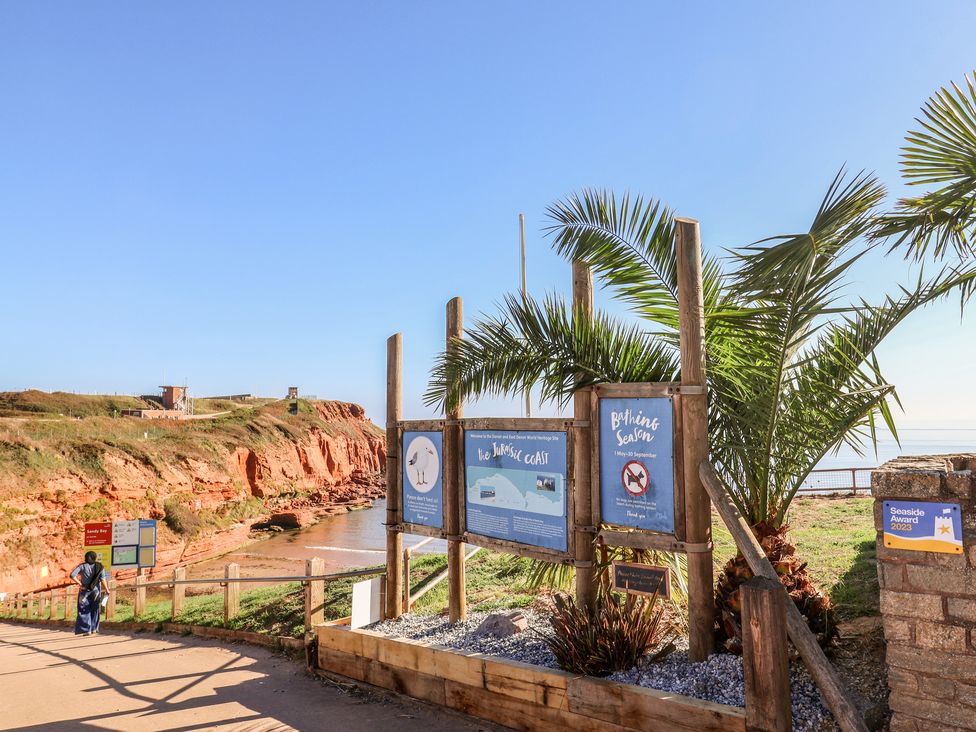 An outdoor sign and palm tree along a coastal path at Beech Walk 3 Sandy Bay, Exmouth